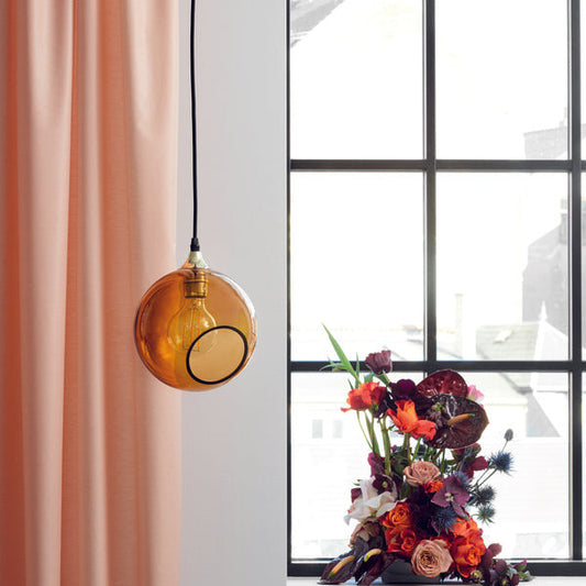 The Ballroom Pendant in amber hanging in a livingroom